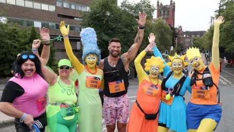 North News Six people dressed in yellow face paint and costumes to look like characters in the Simpsons. In the middle is Jake Quickenden in running year and pink shorts.