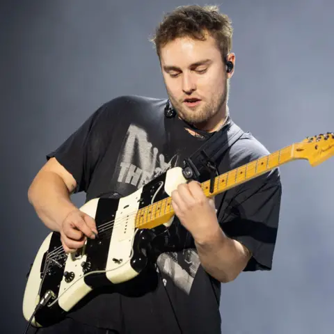 Getty Images Sam Fender on stage playing a black and white striped guitar