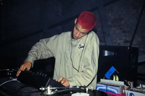 Getty Images Mark Ronson, with his hair dyed red, DJs at an unidentified club in 1993