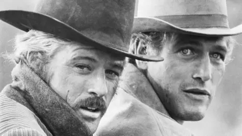 Getty Images Paul Newman and Robert Redford in a black and white still from Butch Cassidy and the Sundance Kid. They are both dressed in cowboy hats.