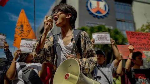 Getty Images A young protester in the Philippines speaks through a megaphone in front of a crowd