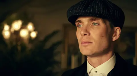 BBC Studios Cillian Murphy in character as Tommy Shelby, wearing the iconic hat and dressed in smart clothing