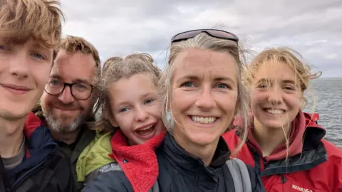 Family handout Family photo of Wren with the sea in the background. 
from left to right we her brother, dad, wren, her mum and her sister. 
all are wearing raincoasts and smiling directly into the camera.