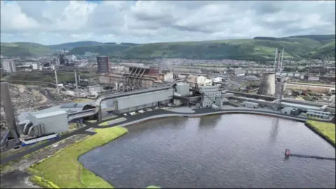 Tata Steel UK An artist’s impression of a future industrial facility near a lagoon, showing large buildings, chimneys and storage tanks. The site is surrounded by green hills under a cloudy sky. It illustrates how the new electric arc furnace might look once operational.