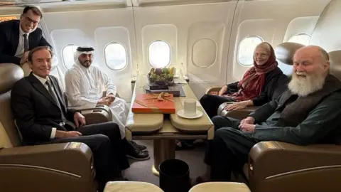 QATARI GOVERNMENT Barbie and Peter Reynolds sitting on a Qatari plane with diplomats 