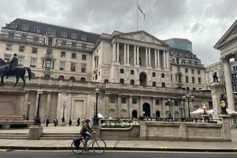BBC A cyclist goes past the exterior of Bank of England which is covered with white Portland stone and has columns and sculptures all over the façade