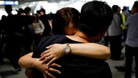 Reuters A South Korean worker who was detained in a huge immigration raid last week in Georgia, hugs a family member in the parking lot at the Incheon International Airport in Incheon, South Korea on 12 September.