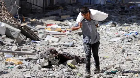 Reuters Palestinian boy carries a bag with flour at Sabra neighbourhood, following Israeli operation, in Gaza City, October 8, 2025