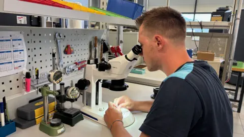 MPS An MPS worker with short hair looks into a microscope