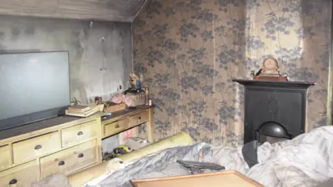 Electrical Safety First The Chilworth home of Emma Wills after a modified e-bike caused a fire which destroyed much of the property. The bedroom in the image has a black wall and destroyed wallpaper.