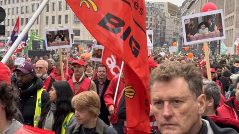 Bruno Boelpaep/BBC A large number of protesters with red flags fills the street