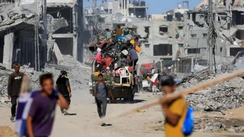 Reuters Palestinians on a vehicle pass by the rubble of destroyed buildings in Gaza City 