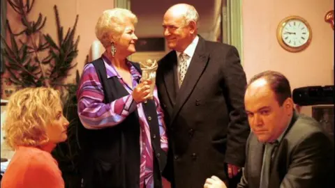 Four characters from a scene from Eastenders in 2001 sat in a front room played by Lucy Speed, Pam St Clement, Tony Caunter and Shaun Williamson