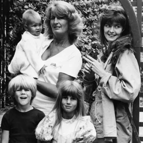 Hulton Archive via Getty Images A black and white photo from 1981 of Lady Annabel with a baby in her arms, two small children standing in front of her and an young woman by her side. 