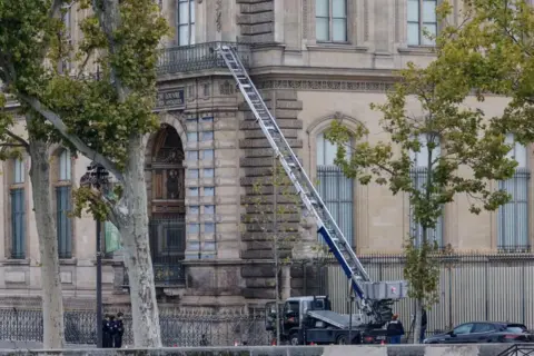 EPA/Shutterstock French police officers stand next to a mechanical ladder used by robbers to enter the Louvre Museum via a balcony.