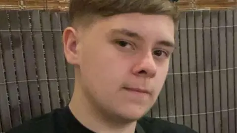 Family handout A teenage boy with dark hair. He is starting into the camera. A fence is behind him.