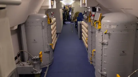 A plane interior is shown with military equipment 