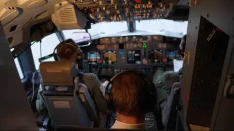 The back of a man's head is pictured with the interior of an aircraft cabin in the background