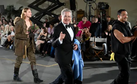 Getty Images Kyle MacLachlan in black tie point to the camera and smiling as he walks along the at the Vogue World Hollywood event
