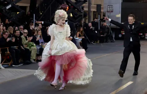 Getty Images Julia Garner in a large frilly cream dress walking the runway at the Vogue World show