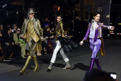 Getty Images 3 models in stride confidently wearing flamboyant outfits