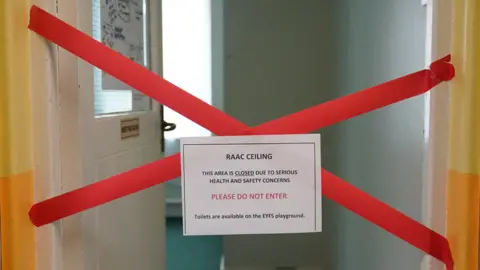 PA Media A classroom with an open door and red tape in a cross over the doorway warning about a Raac ceiling and saying "please do not enter".