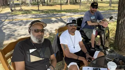 BBC Troy Williams, Marcellus Brothers and Jonathan Giba sit outside the military hospital wearing sunglasses