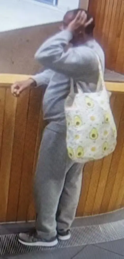 Met Police Hadush Kebatu is seen wearing a grey tracksuit holding a white bag with avocadoes. 