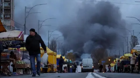 Reuters A man walks around a market as a fire burns at the site of a missile strike