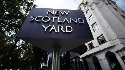 EPA New Scotland Yard sign shows silver lettering on black backdrop in front of a sandy coloured building