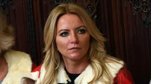 Getty Images Michelle Mone has long blonde gong over the shoulders of her House of Lords gown