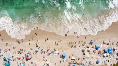 Kevin Carter/Getty Images  In an aerial view, people celebrate the Fourth of July along the coast of La Jolla's Windansea Beach on a warm summer day on July 4, 2023 in San Diego, California