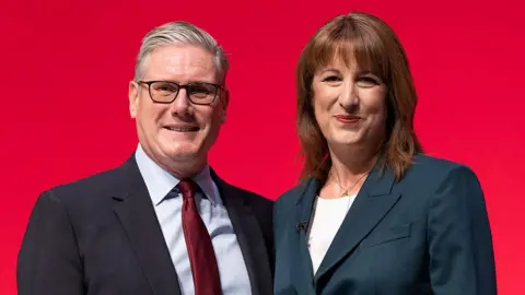 Getty Images Sir Keir Starmer and Rachel Reeves stand alongside each other against a red backdrop at Labour's annual party conference in September.
