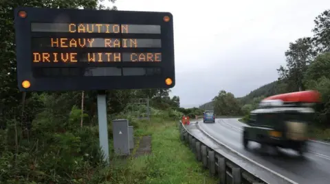 PA Media A sign by a road saying caution heavy rain drive with care