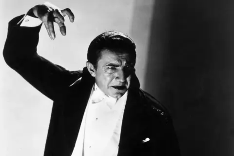 Getty Images Black and white photo of Bela Lugosi as Dracula - in a black dinner suit  looking down and his right arm up - with his hand in a claw