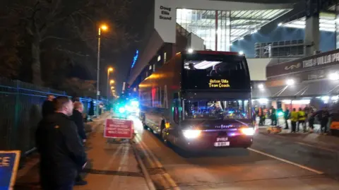 PA Media The Aston Villa team bus arrives before the UEFA Europa League match at Villa Park, Birmingham. It is dark outside and the bus has its lights on in front of the lit-up stadium. The sign says Aston Villa Team Coach.