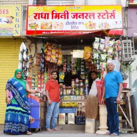 Annesha Ghosh Radha Yadav’s family, including her father Omprakash (first from right), outside Radha Mini General Store in Kandivali, that she opened with her earnings

