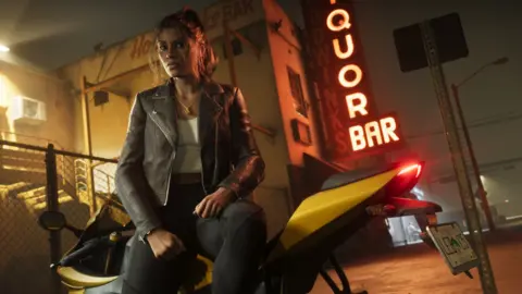 Rockstar Games A screenshot from GTA 6 shows Lucia, at night, sitting on a parked yellow motorbike. She has her hair tied back and wears a leather jacket over a white t-shirt. She's next to a wire fence that surrounds a dirty-looking building with a large, red, glowing sign that reads "Liquor Bar" in the background.