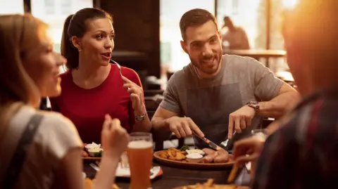 Getty Images Group of happy friends having a lunch in a tavern. 