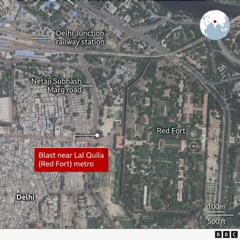 A satellite map of central Delhi showing the location of a blast near Lal Quila (Red Fort) metro station. The Red Fort complex is highlighted on the right, enclosed by walls and green gardens. To the left are densely packed urban areas next to the labeled roads Netaji Subhash Marg. At the top, Delhi Junction railway station is marked.