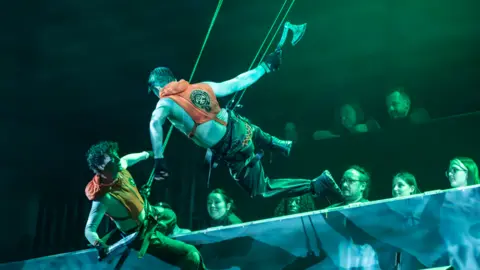 Johan Persson actors clipped to ropes elevated from the stage 