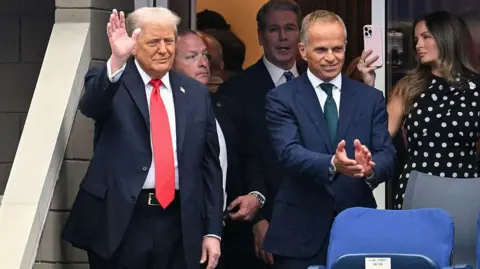 MANDEL NGAN/AFP US President Donald Trump (L), alongside Rolex CEO Jean-Frederic Dufour, waves as he arrives to attend the men's singles final tennis match between Spain's Carlos Alcaraz and Italy's Jannik Sinner on the last day of the US Open tennis tournamen