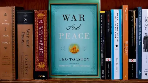 Getty Images A blue-green edition of Leo Tolstoy's War & Peace faces out from a bookshelf with other editions of the novel beside it