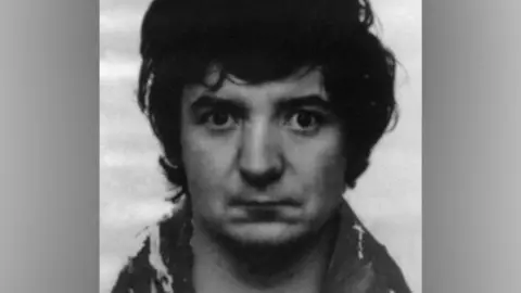 Merseyside Police A black-and-white police mugshot of Peter Sullivan, taken in 1986. In the photograph he has black bushy hair and is wearing a wool coat.