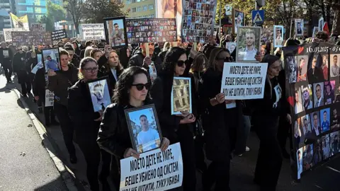AFP via Getty Images Relatives of the victims of a deadly nightclub fire on March 16, 2025 hold photographs of the deceased as they march to demand justice in Skopje on November 15, 2025
