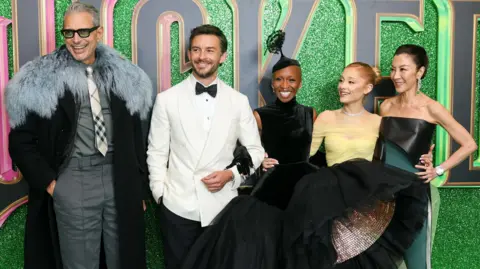 Getty Images Left to right: Jeff Goldblum, Jonathan Bailey, Cynthia Erivo, Ariana Grande and Michelle Yeoh in front of a sparkly green background