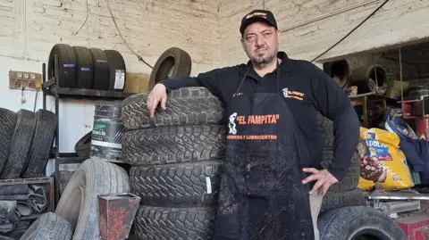 Matías Zibell García Mechanic Fabio Javier Jiménez leaning on tyres at his garage