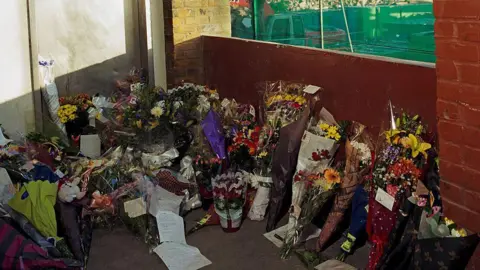 Getty Images Bouquets of flowers left on a stairwell in the North Peckham Estate.