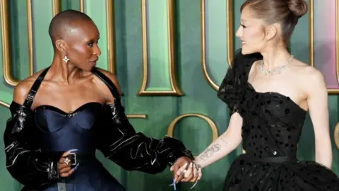 Press Association Cynthia Erivo and Ariana Grande are pictured holding hands and smiling at each other as they arrived for the European premiere in London of Wicked: For Good.