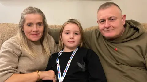 BBC A woman on the left, a child in the middle and a man on the right. 